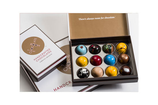 Close up of six stacked mouthwatering brownies in front of a stylish 12 piece brand box of brownies