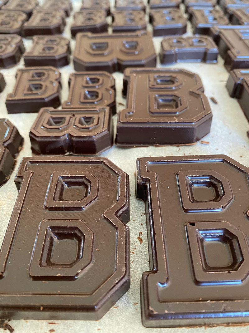 Close up looking down a sheet tray of assorted sizes of chocolate in the shape the letter b