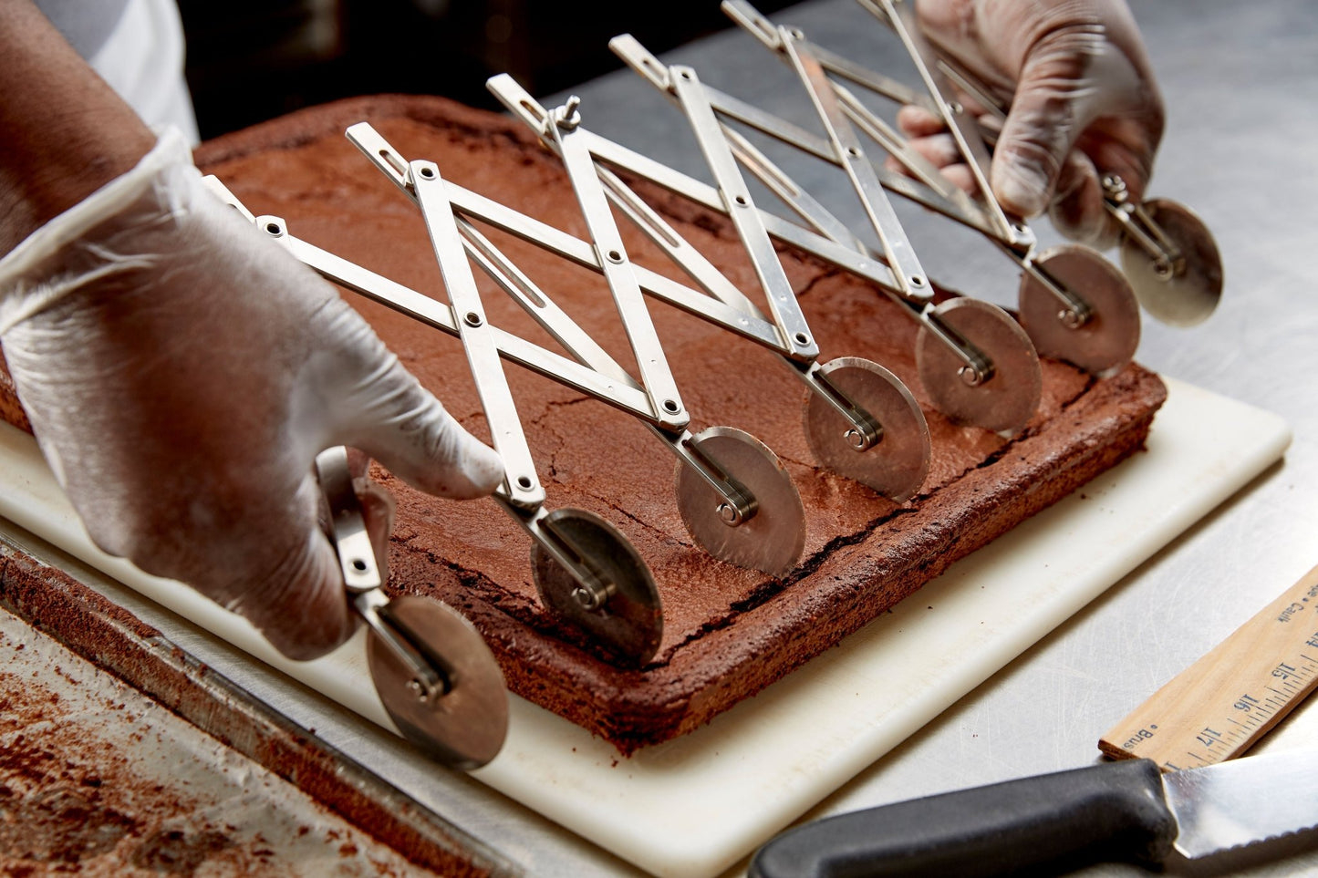 
                  
                    A chef with a pastry roller scoring full tray of brownies that are about to be cut
                  
                