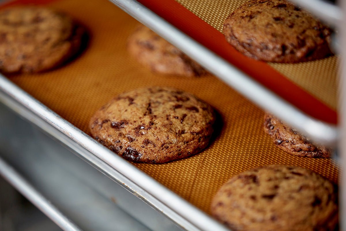 
                  
                    A close up shot of 2 trays of fresh baked chocolate chip cookies on a speedrack
                  
                