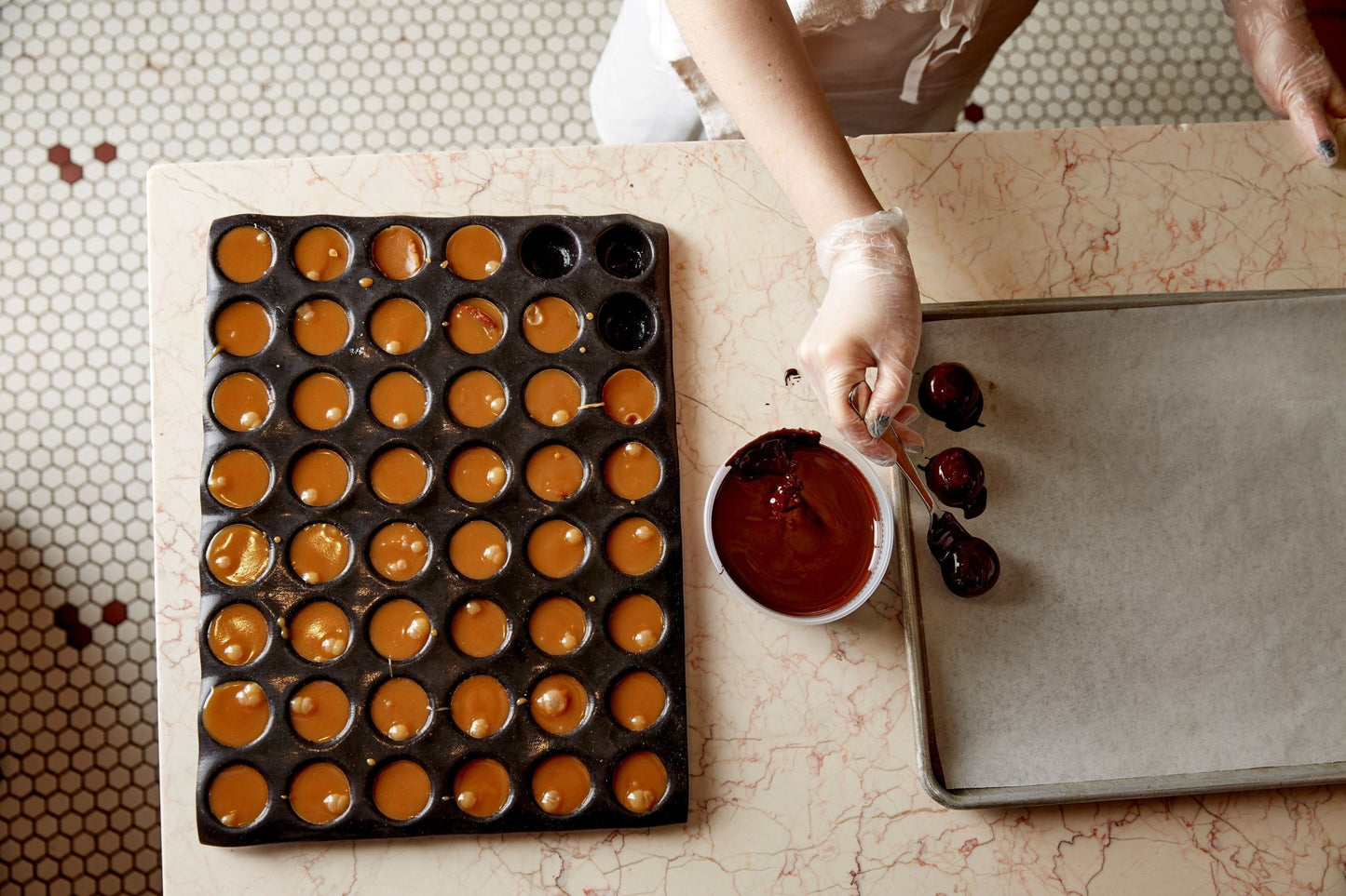 
                  
                    Overhead shot, mold full of s'mores, a container of melted chocolate, a chef putting dipped dark chocolate s'mores on a tray
                  
                