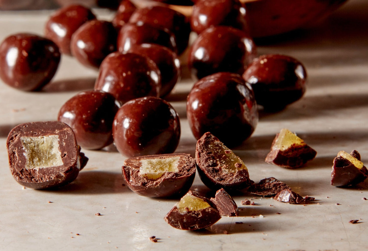 Close up of dark chocolate ginger poured from a wooden bowl some broken open in the front