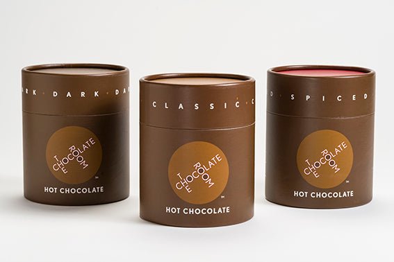 Classic, Dark , and Spiced Hot Chocolate powders in a stylish branded brown containers with a red top