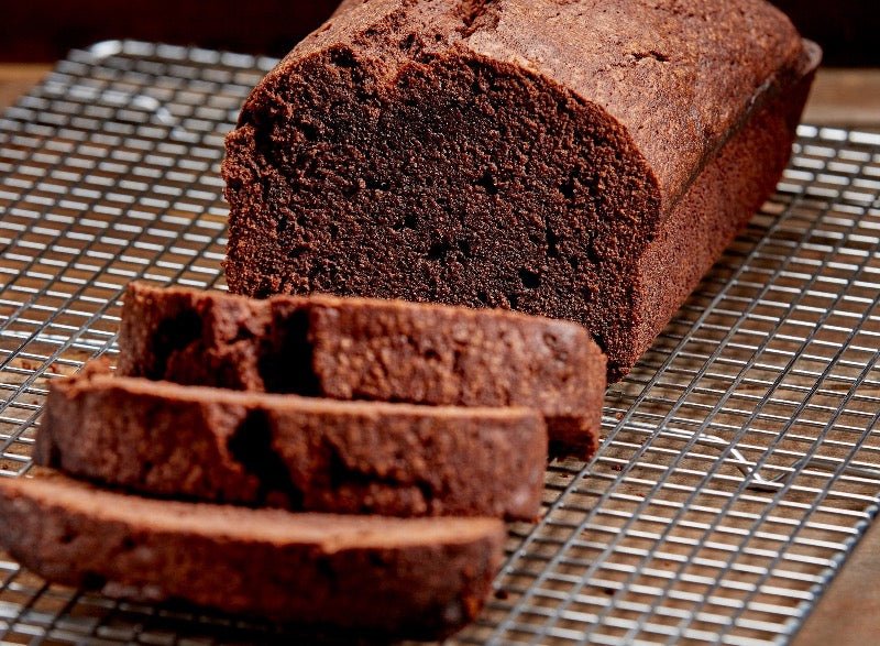 Chocolate pound cake loaf with 3 slices cut sitting on a cooling rack