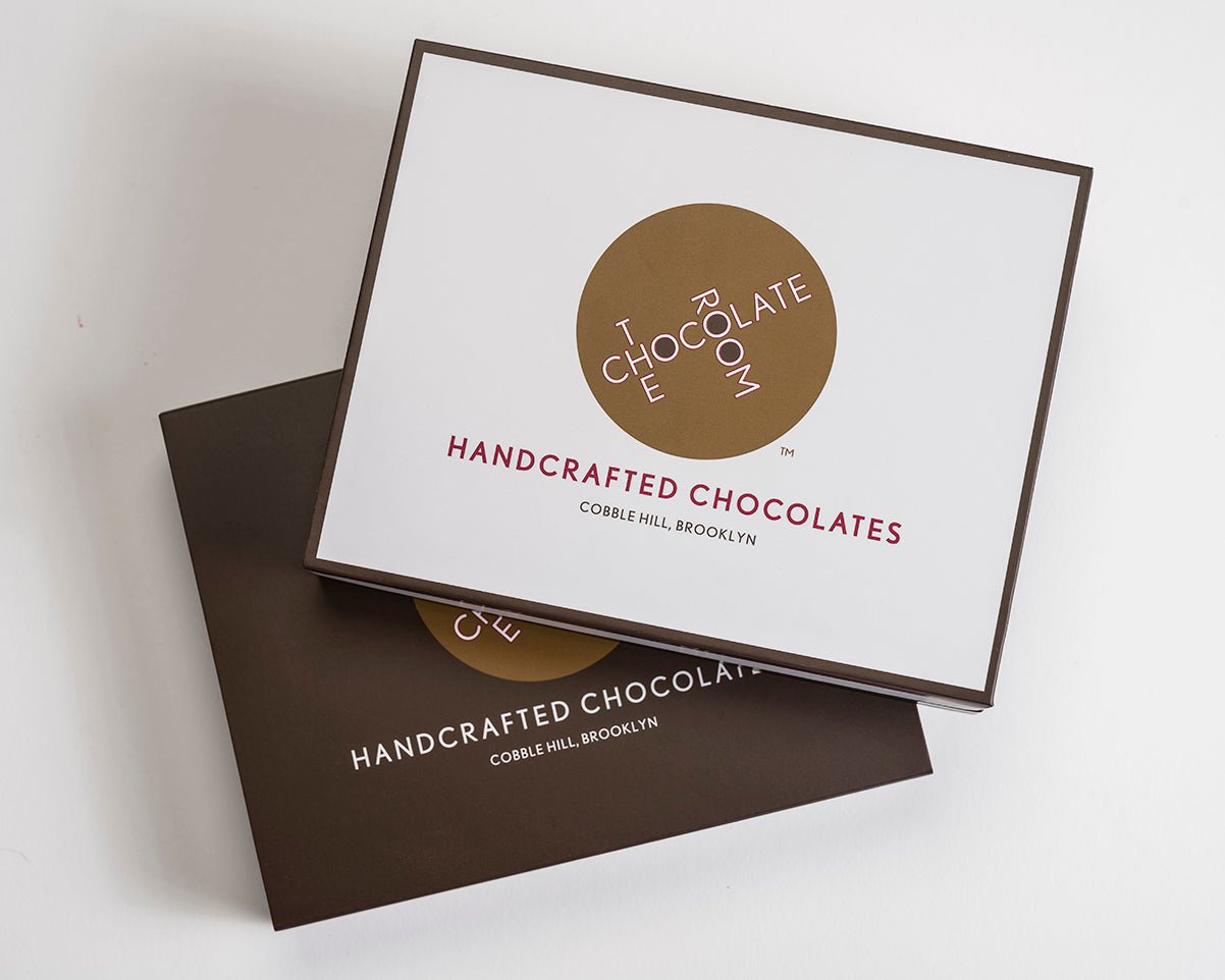 Stack of 2 12 piece bonbon boxes. One shows the box without the sleeve revealing a white box frame in brown with our logo