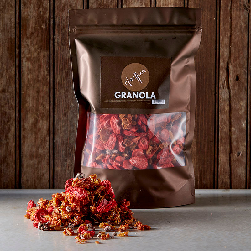 A pile of Chocolate Room Granola with freeze dried strawberries in front of its resealable windowed branded packaging